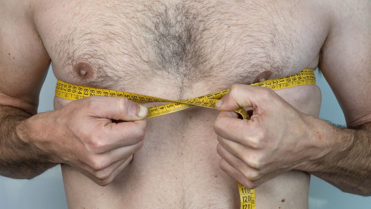 Breast 4 man with chest hair measuring it with tape measure